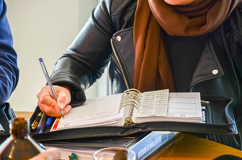 A participant writing in an open My-Tyme planner.